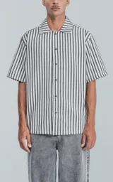 Camisa de manga corta con cuello abierto y calce oversize, a rayas verticales blancas, grises y negras.