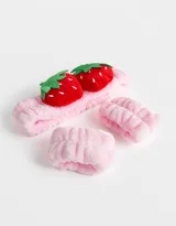 Set de accesorios para el pelo color rosa, compuesto por una vincha con apliques de frutillas y dos muñequeras.