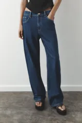 Pantalón de jean azul oscuro, de corte wide leg y tiro medio, con cinco bolsillos y cierre frontal con cremallera y botón metálico.