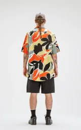 Camisa de manga corta con estampado abstracto en tonos naranja, negro, gris y amarillo. Tiene calce oversize y canesú en la espalda.