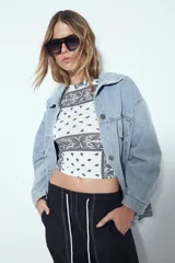 Top crop sin mangas, ajustado al cuerpo, con estampado tipo bandana en tonos rojos y blancos. Presenta cuello cerrado y sisas definidas.