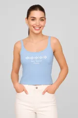 Musculosa blanca de algodón con elastano, breteles finos, corte cropped, cuello redondo y bordado frontal con texto y flores.