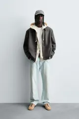 Cazadora de efecto piel color marrón oscuro, corte relajado, con cuello solapa, cierre frontal de botones a presión y bolsillos de vivo en cadera.