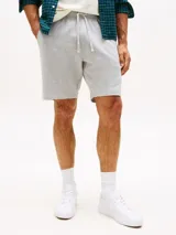 Pantalón corto deportivo gris de felpa, con cintura elástica ajustable con cordón, bolsillos laterales y logo de Tommy Hilfiger bordado en el ruedo.