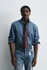 Camisa relaxed fit confeccionada en denim de algodón con cuello solapa, manga larga con puño abotonado, efecto lavado medio y cierre frontal con botones.