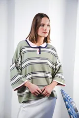 Remera de algodón y poliéster a rayas horizontales rojas y azul marino sobre fondo crudo. Tiene cuello tipo polo con botones, mangas amplias y corte oversized.