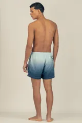 Short de baño con degradé de celeste a azul marino, con cintura elástica ajustable, dos bolsillos laterales y uno trasero con cierre. Cuenta con suspensor de malla fina hipoalergénico y protección UV 50.