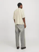 Polo de manga corta color crema con rayas verticales en relieve color verde claro. Tiene cuello clásico y cierre frontal con botones.