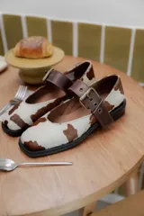 Zapatos tipo Mary Jane color marrón con hebilla dorada y punta cuadrada.