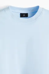 Remera celeste de algodón, corte cuadrado y holgado, con cuello redondo ribeteado.