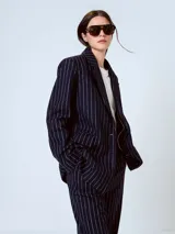 Blazer azul marino con rayas verticales blancas, de corte clásico, con solapas de muesca, cierre frontal con dos botones, bolsillos con solapa y abertura en la espalda.