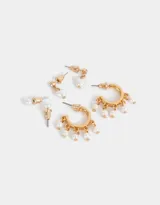 Set de tres pares de aros dorados: un par de aros pasantes con perlas, un par de aros con dije de corazón con perla y un par de argollas con colgantes de perlas.