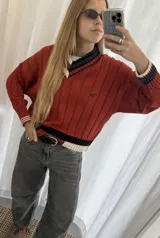 Buzo tejido verde con escote en V, cuello con rayas blancas y azul marino, y puños y ruedo con detalle de rayas.