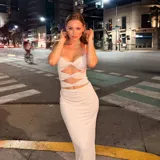 Vestido largo color beige con escote halter, espalda descubierta y aberturas en el abdomen.