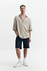 Camisa negra oversize de manga corta con cuello clásico y bolsillo en el pecho.