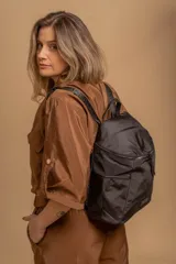 Mochila urbana de diseño compacto, color violeta/malva, con acabado ligeramente brillante. Presenta un compartimento principal con doble cierre superior y bolsillos laterales con cierre.