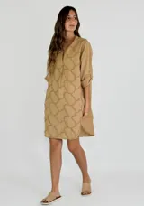 Vestido corto color beige con estampado de formas geométricas en relieve, escote en V y mangas largas.