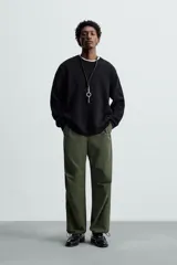 Pantalón verde militar de corte relaxed fit confeccionado en tejido técnico ligero. Cuenta con cintura elástica ajustable con cordón interior, bolsillos frontales y traseros con solapa, pliegues en las rodillas y bajo ajustable con elástico.