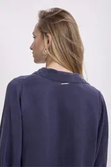 Camisa color verde oliva, de corte recto, con cuello camisero y mangas largas con puños abotonados.