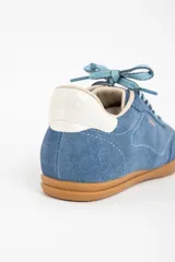 Zapatillas deportivas de gamuza color celeste con cordones celestes y suela marrón.