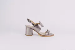 Sandalias plateadas de cuero con taco ancho y diseño de ondas en el empeine. Cierre con hebilla en el tobillo.