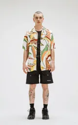 Camisa de manga corta con calce oversize y estampado abstracto en tonos naranja, verde, amarillo y marrón.