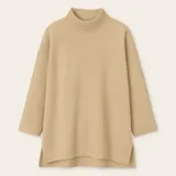 Sweater negro de tejido texturizado, con cuello alto, mangas 3/4 y corte asimétrico con aberturas laterales.