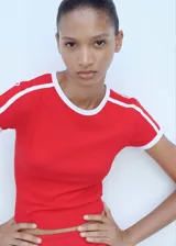 Remera roja de corte recto con cuello redondo y mangas cortas con terminaciones en contraste blanco. Presenta dos líneas blancas paralelas en los hombros.