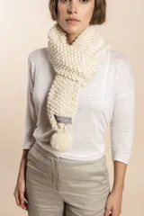 Bufanda tejida a mano en punto arroz color beige, con pompones en los extremos.