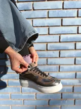 Zapatillas deportivas de cuero color peltre, con suela blanca y diseño moderno.