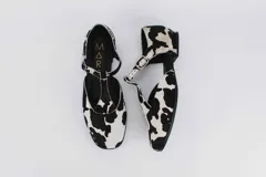 Zapato flat de cuero con estampado de vaca en blanco y negro, con tira delantera y hebilla lateral.