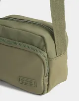 Bandolera negra de tela deportiva con bolsillo frontal con cierre, correa regulable y tag de goma.