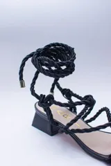 Sandalias doradas con tiras de cuerda para atar al tobillo.