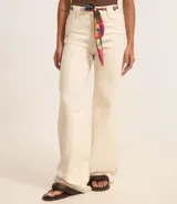 Pantalón wide leg color crudo, confeccionado en sarga de algodón, con trabillas en la cintura, cierre tradicional, bolsillos y costura contrastante aparente. Incluye cinturón pañuelo estampado.