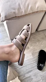 Sandalias bajas color rosa viejo con tiras de cuero entrelazadas y suela marrón.