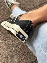 Zapatillas bajas de lona color blanco, con cordones marrones, puntera de goma y base blanca.