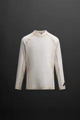 Camiseta de surf blanca de manga larga, confeccionada en tejido técnico elástico con protección solar UPF40+. Presenta cuello alto, corte ajustado y costuras planas. Logo estampado en la manga.