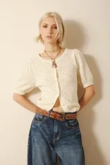 Cardigan color crema de punto calado con mangas cortas abullonadas y cierre frontal con botones.