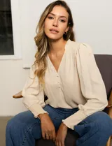 Blusa color beige de gasa con escote en V, apliques de botones y detalle de punto smock en hombro y puño.