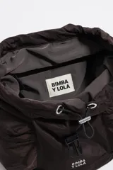 Mochila de nylon color marrón oscuro, con estructura blanda, cierre principal mediante cordón y solapa superior asegurada con hebilla de plástico gris. Posee dos bolsillos frontales con fuelle y asas ajustables.