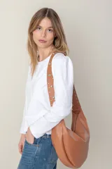 Cartera negra tipo banana confeccionada en cuero vacuno, con cierre superior y asa con tachas plateadas.