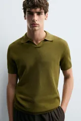 Jersey de punto color verde oliva, de calce relajado (relaxed fit), con cuello solapa y abertura frontal en forma de V. Es de manga corta y presenta acabados en rib en puños y ruedo.