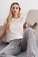 Remera blanca de lino y viscosa con mangas cortas y calce relajado. Presenta bordados de canutillos, lentejuelas y mostacillas en los hombros.