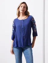 Blusa azul con escote redondo, mangas 3/4 con bordado floral y abertura central con botones. Marca Forgotten Grace.