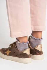 Zapatillas bajas de cuero color marrón con estrella beige en el lateral, cordones color beige y detalle dorado en el talón.