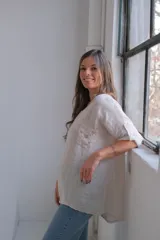 Blusa beige de lino con cuello redondo, mangas cortas con botón y bolsillo en el pecho con detalle de lentejuelas.