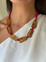 Collar corto con cuentas de cristal checo color ámbar y cuentas redondas rojas. Se cierra con cadena de acero quirúrgico y gancho regulable.