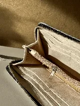 Billetera grande de cuero color verde oliva con correa de hombro desmontable. Tiene espacio para tarjetas, billetes, documentos y un bolsillo con cierre.