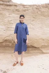 Vestido camisero azul de largo midi, con cuello mao con volados y mangas 3/4. Tiene cierre frontal con botones y un bolsillo de crochet aplicado.