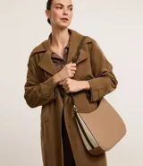 Bolso hobo mediano color beige, con asa corta al hombro y asa larga desmontable. Cierre superior con cremallera y detalles laterales contrastantes.